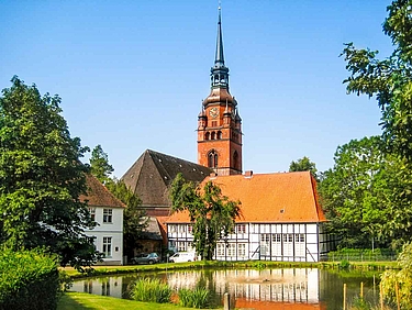 Kleiner Teich umgeben von Grün und im Hintergrund die alte Zierzienserinnenabtei in Itzehoe